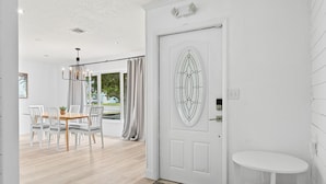 Un intérieur moderne avec une porte blanche, un coin repas comprenant une table et des chaises, ainsi qu’une petite table blanche.