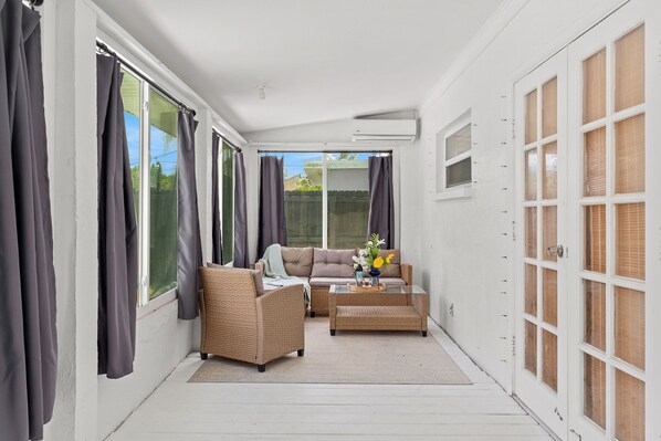 A sunlit patio with wicker furniture, a sofa, and a coffee table. - Family-Friendly Beach House – Private Pool, Balcony, BBQ Grills & Prime Location! (Cocoa Beach)