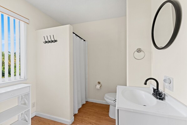 A bathroom with a toilet, sink, and shower.
