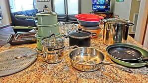 A kitchen counter with various pots and pans, a television, and a couch in the background. - Shelter from the Storm | Weeki Wachee Riverfront Escape (Weeki Wachee)
