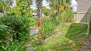 A garden with a stone pathway, various plants, and a small pond. - Shelter from the Storm | Weeki Wachee Riverfront Escape (Weeki Wachee)