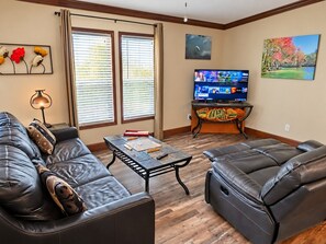 A living room with a leather sofa, a coffee table, a flat-screen TV, and artwork on the walls.