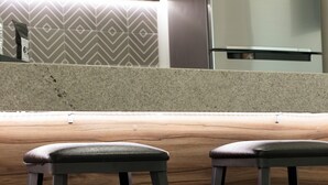 Una cocina con un refrigerador de acero inoxidable, una encimera de madera y dos taburetes negros.