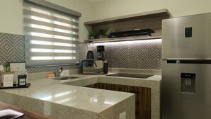 Una cocina moderna con refrigerador de acero inoxidable, cafetera integrada y encimera de granito.