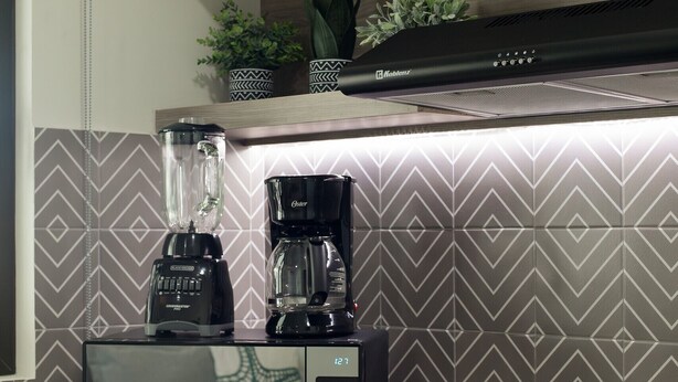 Una cocina con microondas, licuadora y cafetera sobre la encimera.