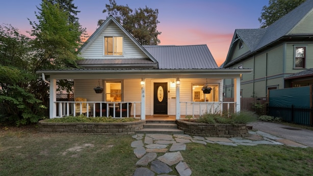 Une maison à deux étages, avec un chemin de pierre menant à la porte d’entrée, entourée d’une pelouse bien entretenue et d’une clôture en bois.