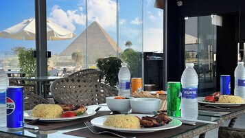 A table set with food and drinks, overlooking a view of pyramids.