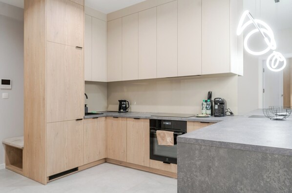 Una cocina moderna con alacenas de madera clara, encimera gris y lavavajillas empotrado.