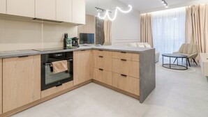 Une cuisine moderne avec des meubles en bois, un four encastré et une machine à café.