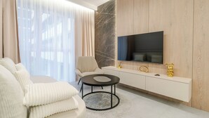 Un salon moderne comprenant un canapé, une table basse ronde, un téléviseur fixé à un mur en bois et une console au design minimaliste.