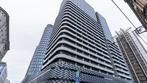 Un immeuble moderne de grande hauteur, doté d’une façade géométrique remarquable et de nombreux balcons.
