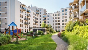 Un immeuble résidentiel doté de nombreux balcons, d’une aire de jeux et d’un chemin pavé.