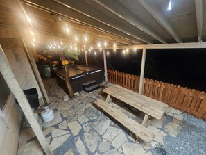 An outdoor patio area with a wooden bench, a hot tub, and string lights. - Country Oasis in the City (Mansfield)