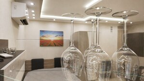 A modern hotel room with a glass table holding wine glasses, a painting on the wall, and a ceiling with recessed lighting. - Elegant Ground-floor Studio With Covered Terrace and Direct Access to Nature (Smolyan)