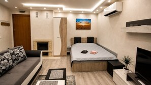 Quarto moderno com cama, sofá, lareira e televisão.