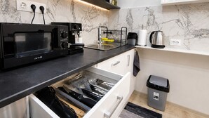 A modern kitchen with a built-in microwave, coffee maker, and kettle, along with a trash bin and a dish rack. - Elegant Ground-floor Studio With Covered Terrace and Direct Access to Nature (Smolyan)