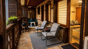 A covered outdoor seating area with two chairs and a table, stone flooring, and a stone wall. - Elegant Ground-floor Studio With Covered Terrace and Direct Access to Nature (Smolyan)