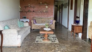 A spacious living area with a stone floor, two sofas, a coffee table, and a brick wall with shelves. - Green retreat with lake, swimming pool, barbecue and large leisure area surrounded by nature (Canguera)