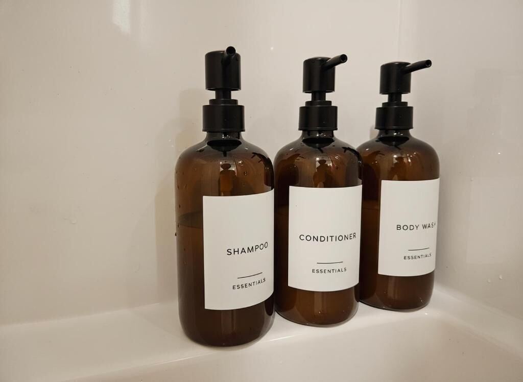 Three bottles of shampoo, conditioner, and body wash on a shelf.
