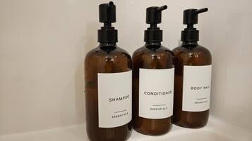 Three bottles of shampoo, conditioner, and body wash on a shelf.