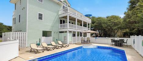 A two-story house with a balcony and a swimming pool.