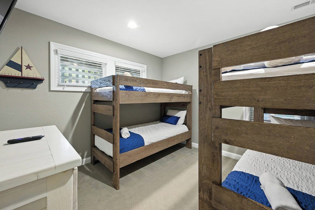 A room with bunk beds, a desk, and a window with blinds.