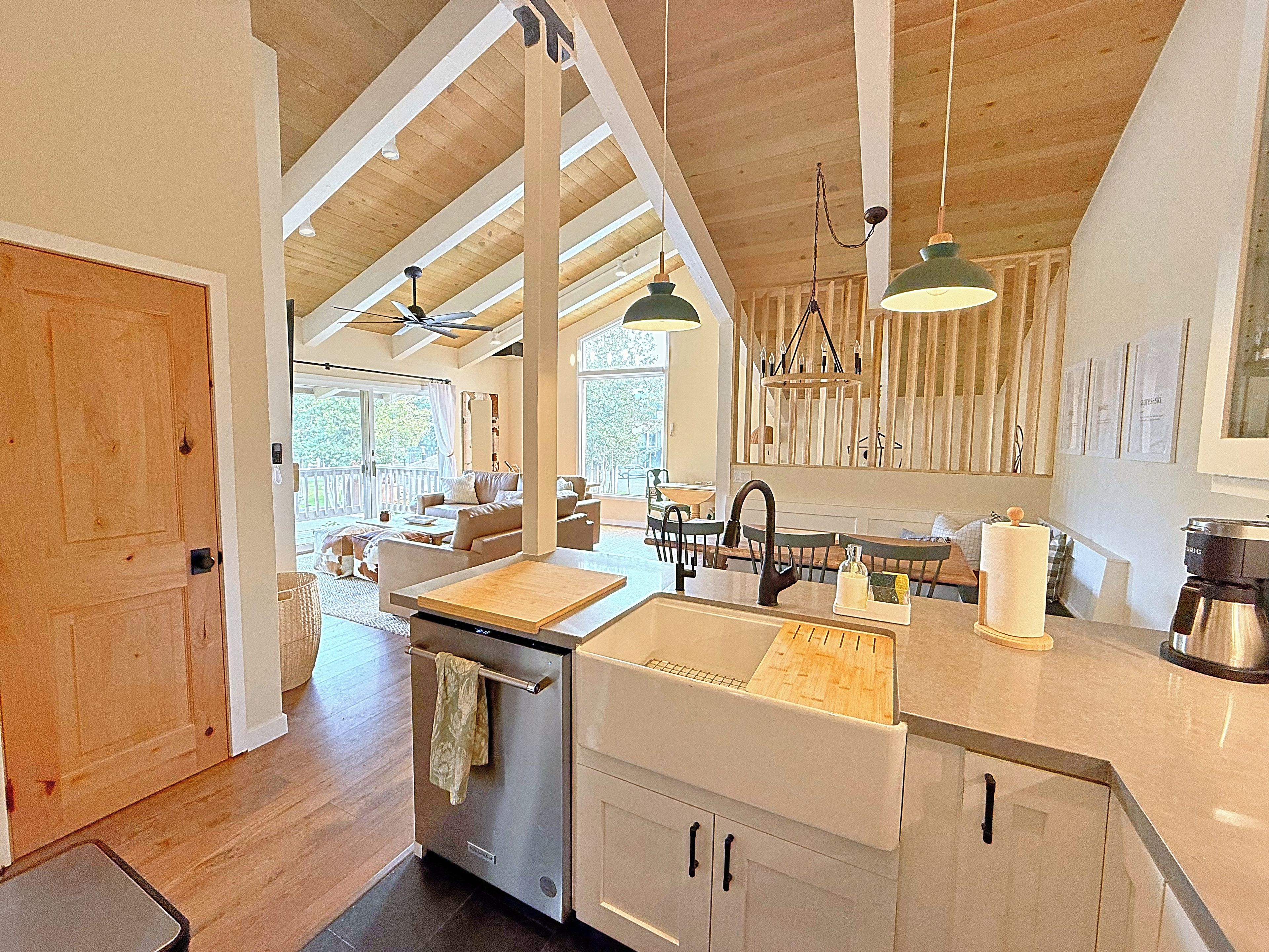 A modern kitchen with a central island, wooden ceiling beams, and pendant lighting.