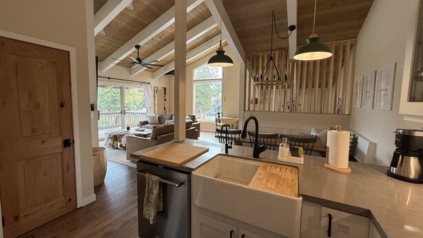 A modern kitchen with a central island, wooden beams, and a dining area with a view.