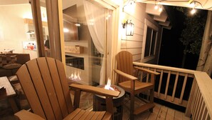 A wooden deck with Adirondack chairs and a fire pit.