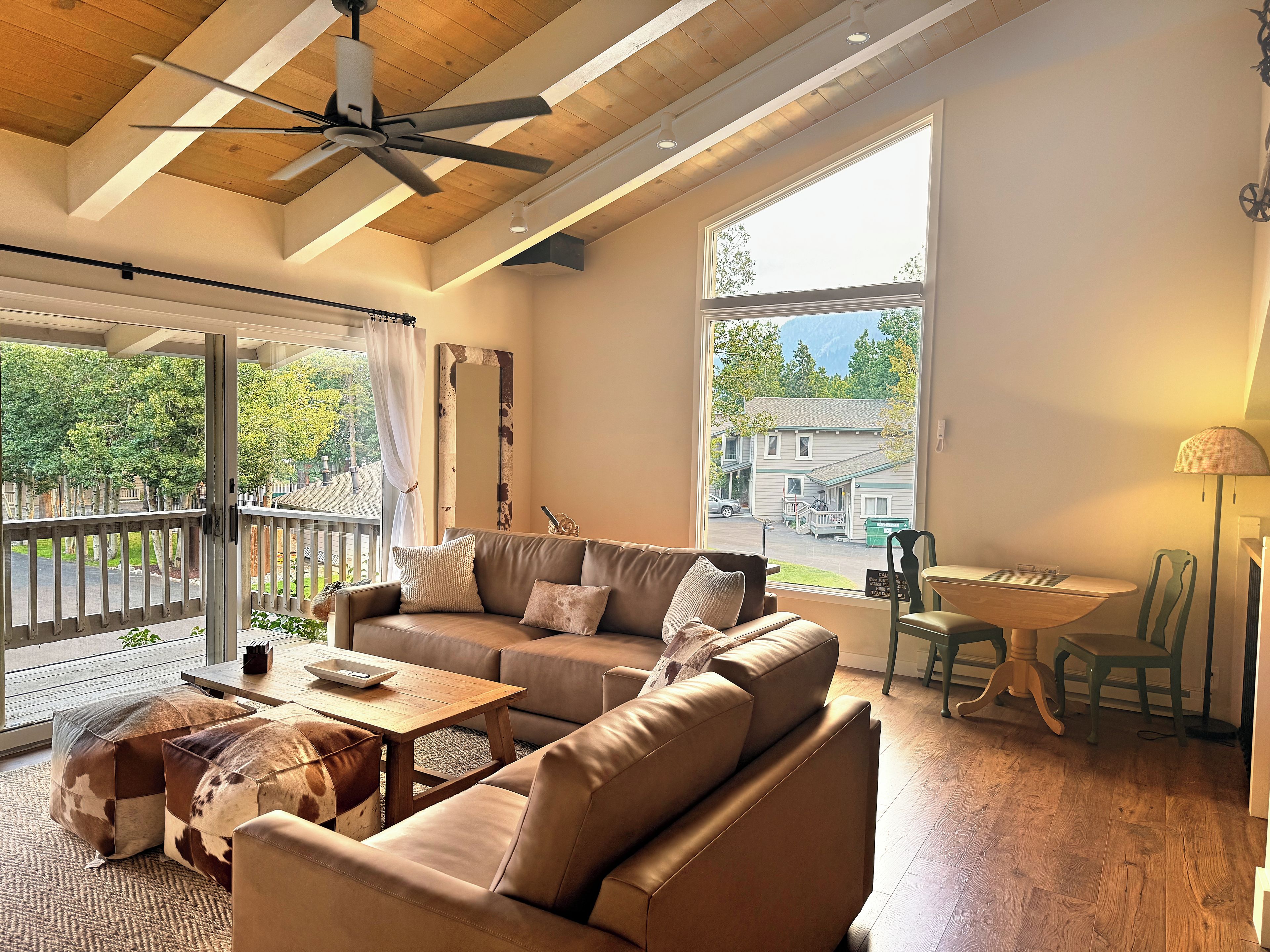A living room with a sofa, coffee table, and a view of a house through a large window.