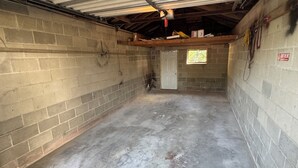 Un sous-sol aux murs en béton, non aménagé, avec une porte et une petite fenêtre.