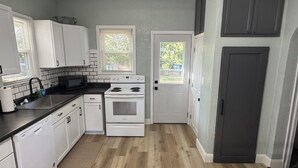 Une cuisine avec des meubles blancs, une cuisinière et un lave-vaisselle.