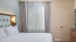 A hotel room with a bed, a nightstand, a dresser, and a window with curtains. - Marriott Vacation Club, Waikiki (Studio) (Honolulu)
