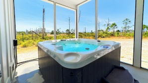 A hot tub with a clear view of the surrounding landscape through large windows.