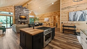 Una cocina amplia con una isla central, chimenea y comedor con sofá y mesa.