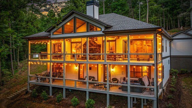 Una casa de madera de dos pisos con balcón, luces colgantes y una chimenea de piedra.