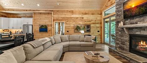 A spacious living room with a large sectional sofa, a fireplace, and a view of the outdoors.