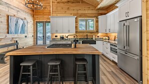 Una cocina moderna con una isla grande, electrodomésticos de acero inoxidable y paredes de madera.