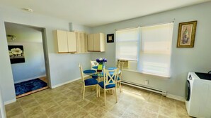 A compact kitchen with a dining area, a built-in oven, and a window with blinds.