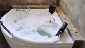 A white bathtub filled with bubbles and a green liquid, with a black towel and a faucet. - MAXIMUM COMFORT (Distrito de Chilca)