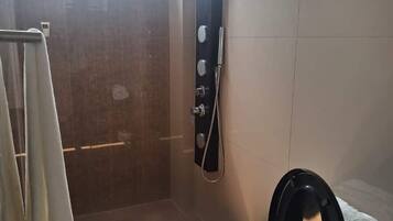 Een badkamer met douche, toilet en handdoekrek.