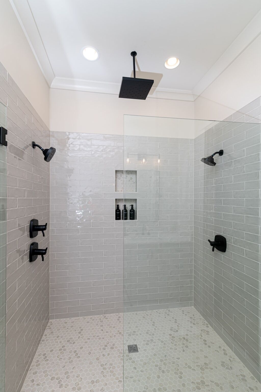 Une douche moderne avec une paroi en verre, des spots encastrés au plafond et un carrelage au sol.