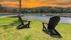 Due poltrone Adirondack rivolte verso un lago, con un pontile e un edificio sullo sfondo.