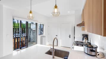 Una cocina moderna con una isla central, electrodomésticos de acero inoxidable e iluminación colgante.