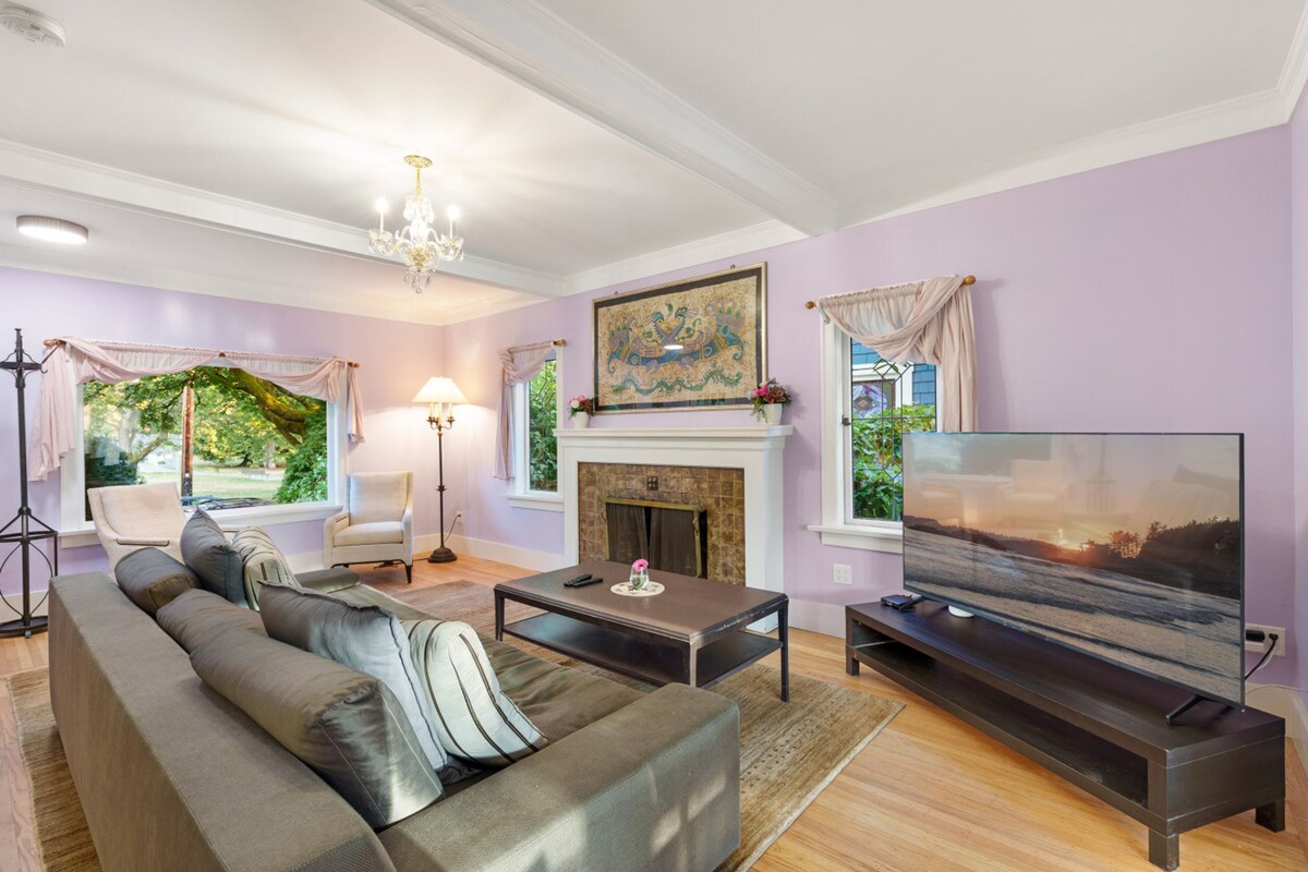 A living room with a sofa, a fireplace, a television, and a chandelier.