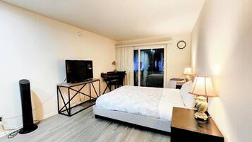 Ein Hotelzimmer mit einem Bett, einem Schreibtisch mit Fernseher, einer Lampe und einem Fenster mit Vorhängen.