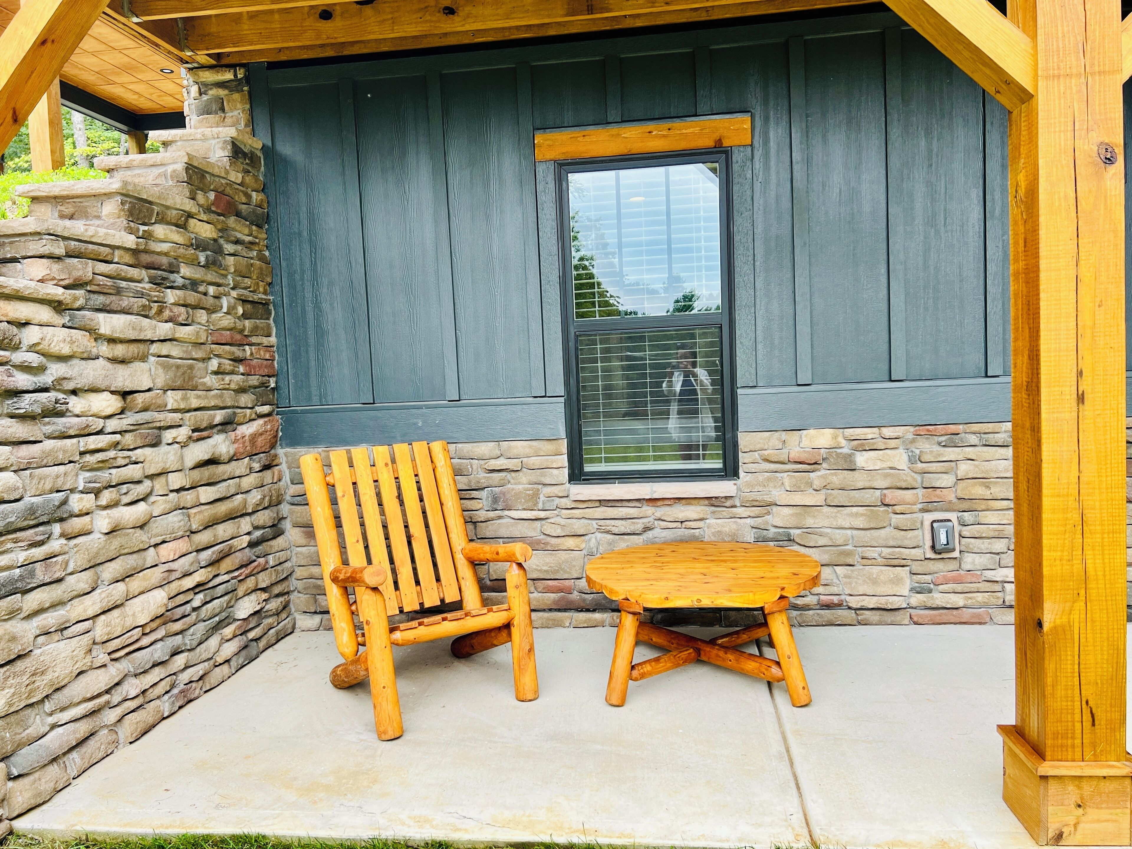 A wooden chair and table set against a stone wall with a window.
