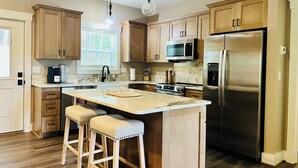 Una cucina moderna con mobili in legno, un frigorifero in acciaio inossidabile, un forno a microonde integrato e una grande isola con sgabelli da bar.