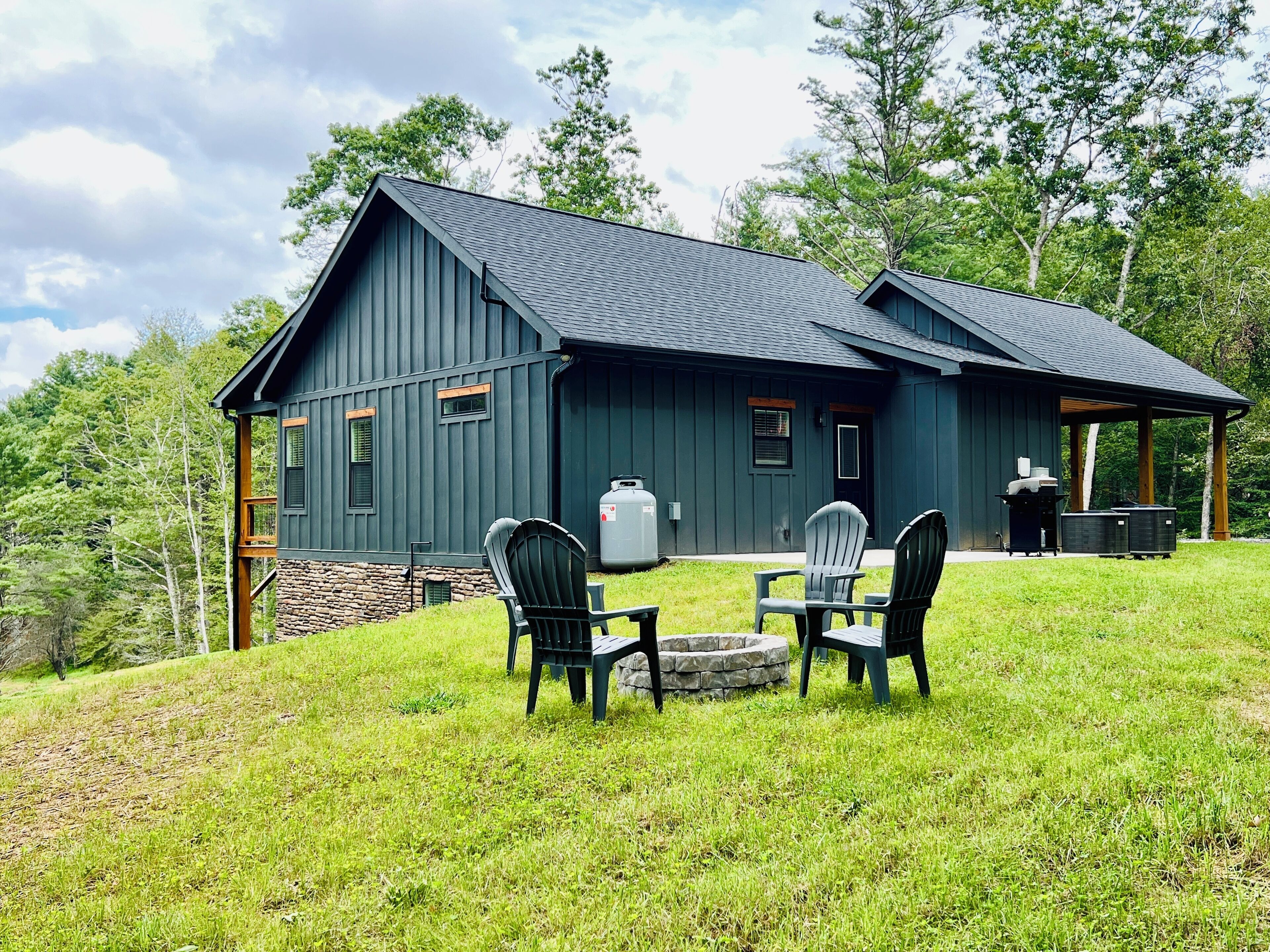 A rustic cabin with a stone foundation, a dark wooden exterior, and a covered porch area.