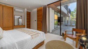 Un dormitorio moderno con una cama grande, un armario de madera, un espejo y una puerta corrediza de vidrio que da a una zona de estar al aire libre.